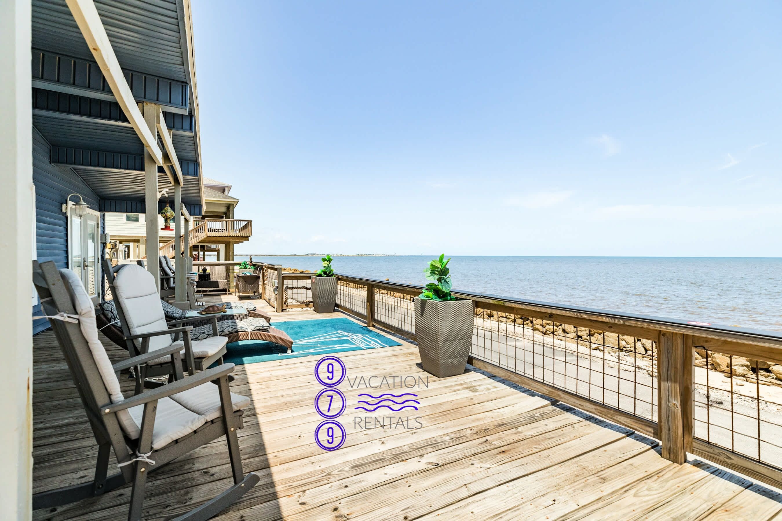 Una terraza de madera con mobiliario exterior, una piscina y vista al mar.