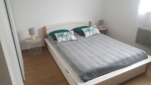 A bedroom with a bed, two nightstands, a lamp, and a radiator.