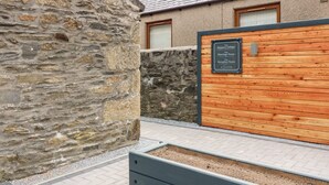 Un muro de piedra, una valla de madera y un letrero que indica 'The Keeper's Cottage' y 'The Marriage Room'.