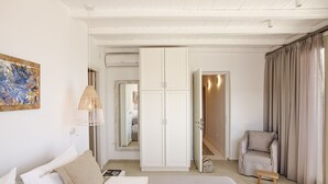 A bedroom with a bed, a chair, a wardrobe, and a painting on the wall.