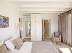 A bedroom with a bed, a chair, a wardrobe, and a painting on the wall.