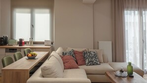 Ein modernes Wohnzimmer mit einer Couch, einem Esstisch und einer Küchenzeile mit einem Fenster.