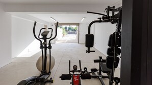 A gym with exercise equipment including a treadmill, elliptical, and weight machines. - Impeccable design, total privacy & heated pool with sea views (Rethymno)