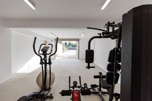 A gym with exercise equipment including a treadmill, elliptical, and weight machines.