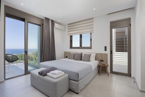 A modern bedroom with a large bed, a balcony with a view, and a sliding door.