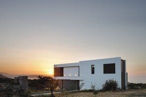 A modern two-story building with a flat roof, large windows, and a stone facade.