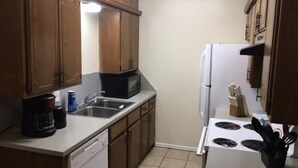A kitchen with wooden cabinets, a microwave, a sink, a dishwasher, a stove, and a refrigerator. - Fort Sill visitor entrance half a mile! (Lawton)