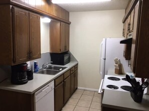 A kitchen with wooden cabinets, a microwave, a refrigerator, a sink, and a dishwasher. - Fort Sill visitor entrance half a mile! (Lawton)