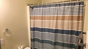 A bathroom with a striped shower curtain, a toilet, and a towel rack. - Fort Sill visitor entrance half a mile! (Lawton)