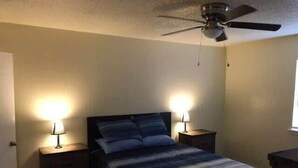A bedroom with a bed, two bedside tables, a ceiling fan, and a window. - Fort Sill visitor entrance half a mile! (Lawton)
