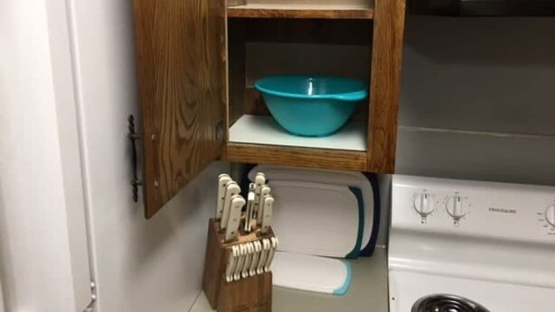 A kitchen with a wooden cabinet, a blue bowl on the shelf, and a knife block. - Fort Sill visitor entrance half a mile! (Lawton)