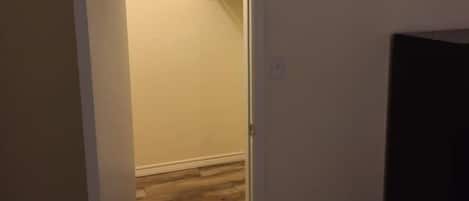 A room with a wooden floor, a white door, and a black object on the right.