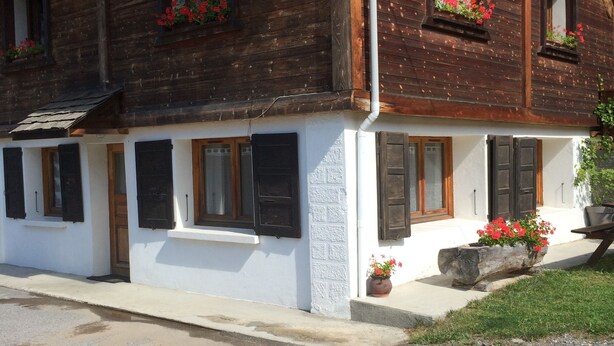 A traditional wooden building with multiple windows, some with shutters, and flower boxes on the windowsills. - Charming T3 in a hamlet (Saint-Gervais-les-Bains)