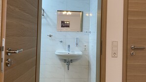 A bathroom with a wooden door, a white sink, and a mirror. - MyHome10, Wiesbaden-Mainz, Apartment No: 6 (Wiesbaden)