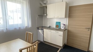 A compact kitchen with a dining area, a dishwasher, and a wooden door. - MyHome10, Wiesbaden-Mainz, Apartment No: 6 (Wiesbaden)