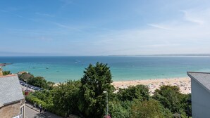 A coastal view with a beach, clear sky, and boats on the water.