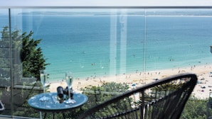 A beach view from a balcony with a table and chairs.