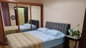 A bedroom with two beds, a bedside table with a lamp and a plant, and a dartboard on the wall. - Niniko's Old Tbilisi Historical House. (Tbilisi)