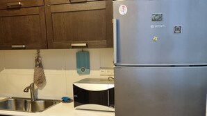 A kitchen with dark wooden cabinets, a stainless steel sink, and a Bosch refrigerator. - Niniko's Old Tbilisi Historical House. (Tbilisi)