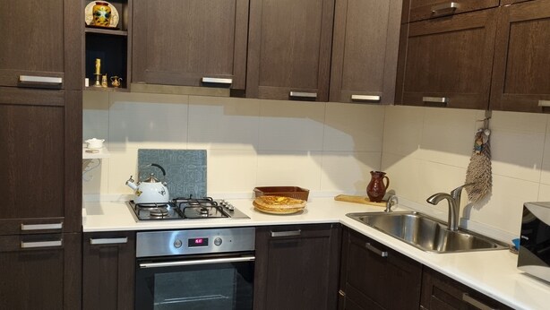 A modern kitchen with dark wooden cabinets, stainless steel appliances, and a tiled backsplash. - Niniko's Old Tbilisi Historical House. (Tbilisi)