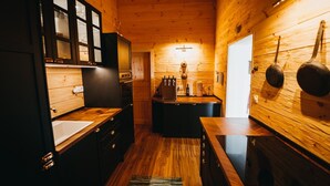 A compact kitchen with wooden cabinets, a central island, and a hanging pot rack.