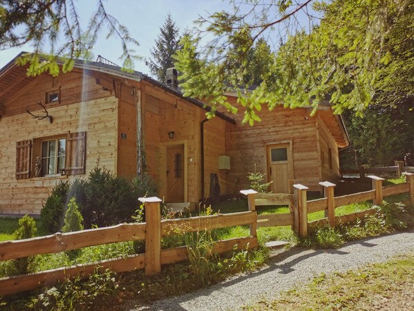 Una cabaña de madera con cerca de madera, una puerta y una ventana.