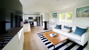 Un salon moderne avec un canapé blanc, une table basse en bois et un tapis à rayures.
