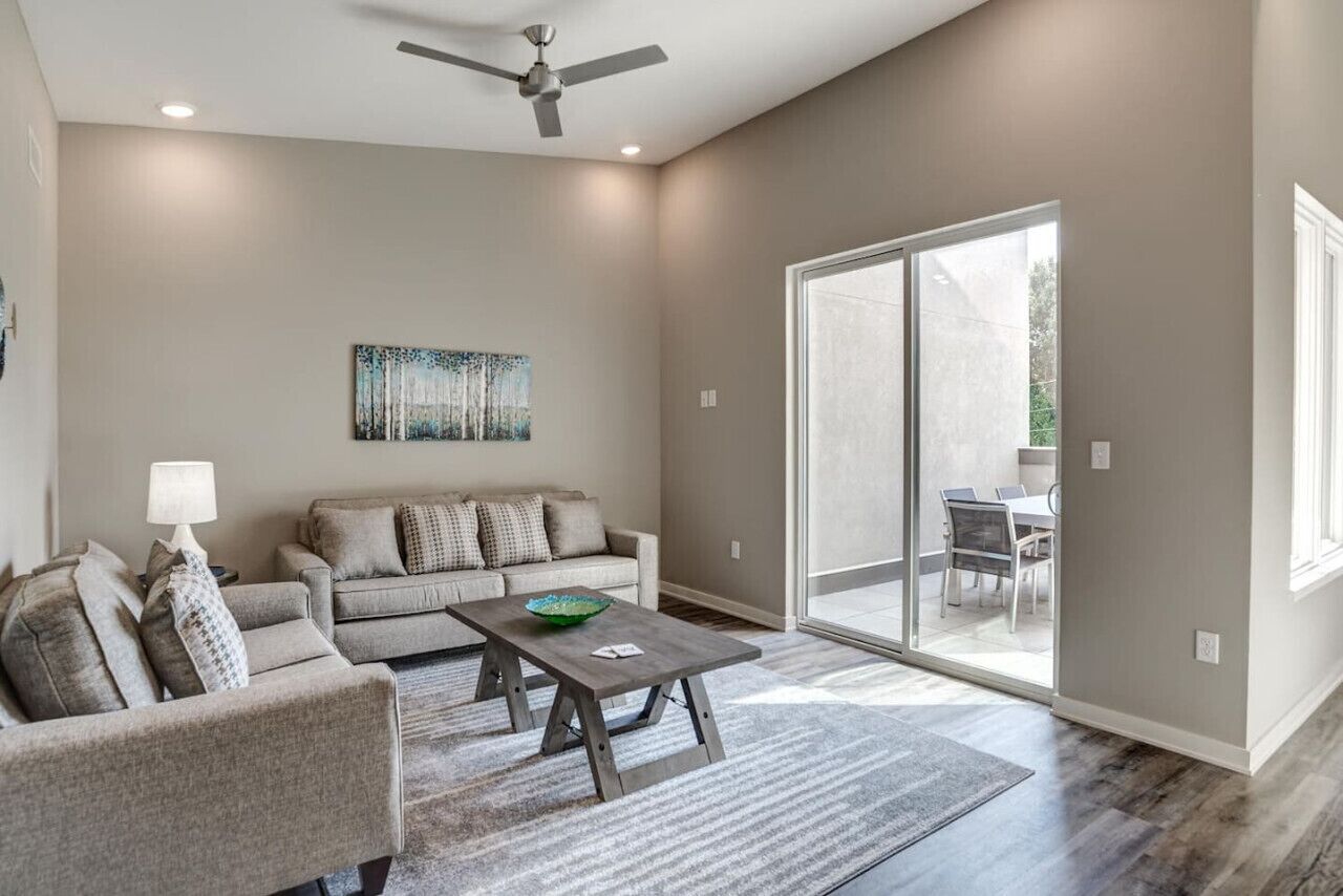 A modern living room with a grey sofa, a wooden coffee table, and a ceiling fan.