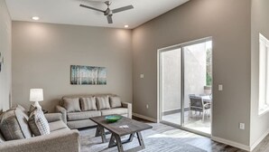 A modern living room with a grey sofa, a wooden coffee table, and a ceiling fan.