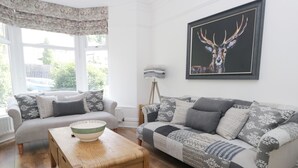 Un salon avec un canapé, une table basse et un tableau représentant un cerf.