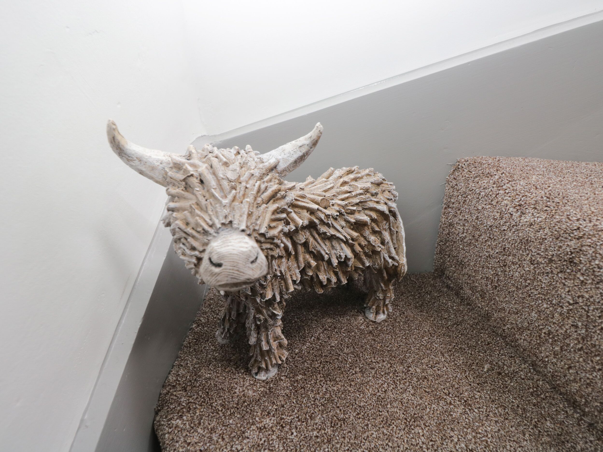 A sculpture of a bull on a carpeted staircase.