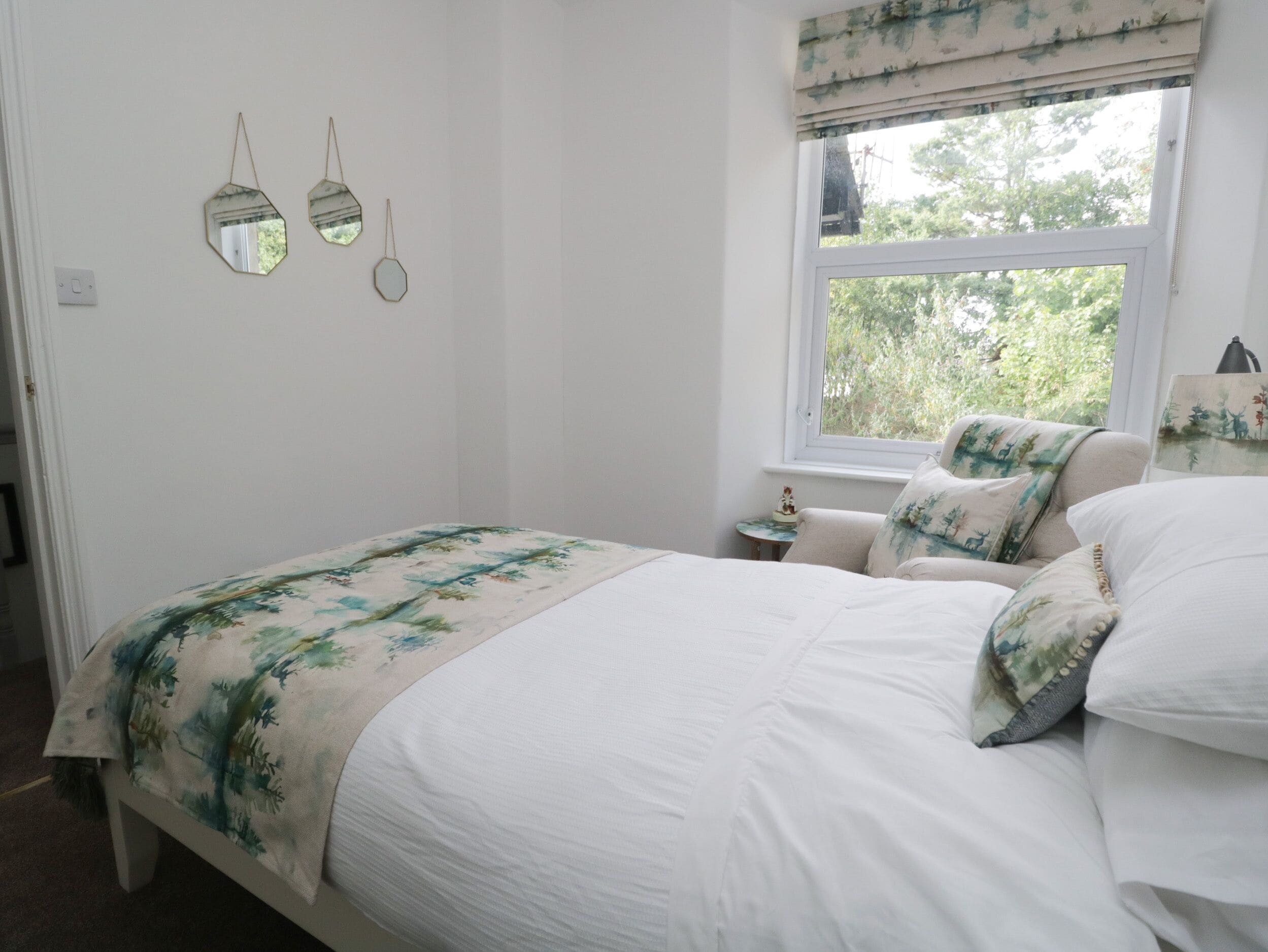 Un dormitorio con cama, mesita de noche y ventana con vista a árboles.