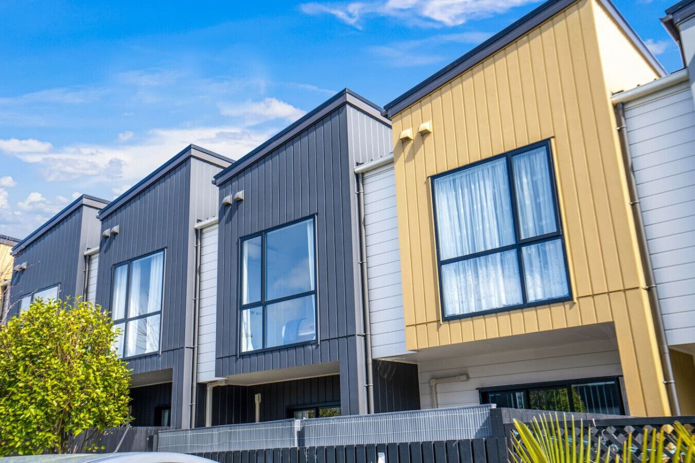 A row of modern townhouses with large windows and a flat roof design.