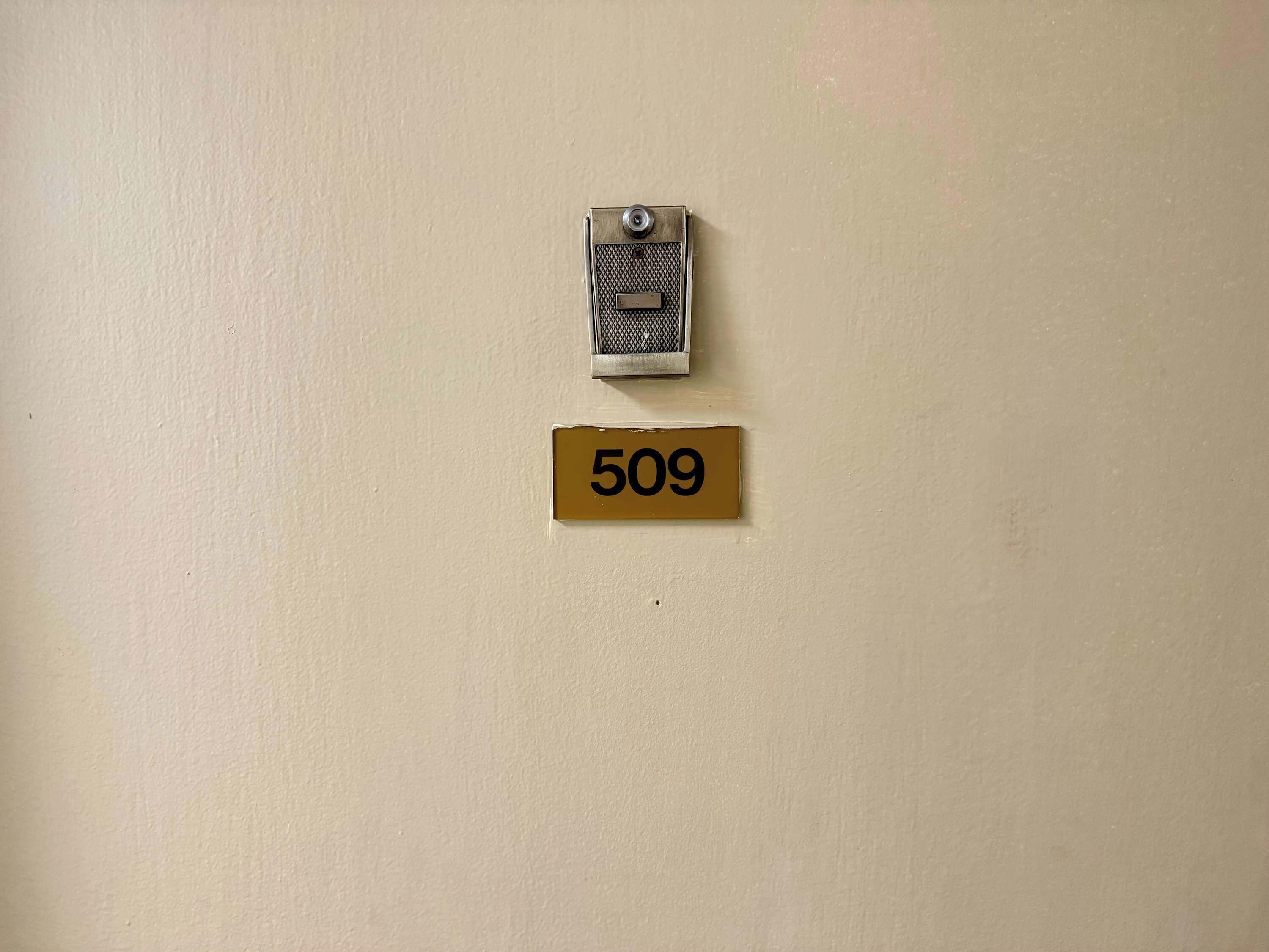 Un interphone fixé au mur et une plaque indiquant le numéro de la pièce.