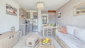 Un apartamento moderno con cocina, comedor y sala de estar. Incluye un sofá, una mesa de comedor y una cocina con microondas y refrigerador.