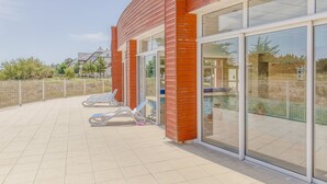 Un edificio moderno con amplios ventanales y un área de piscina con sillones de descanso.