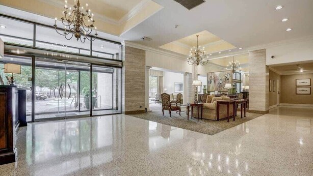 A spacious lobby with a polished floor, a chandelier, and a seating area with a coffee table and chairs.