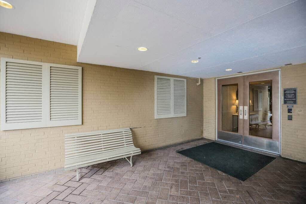 A lobby with a bench, a door with a glass panel, and a tiled floor.
