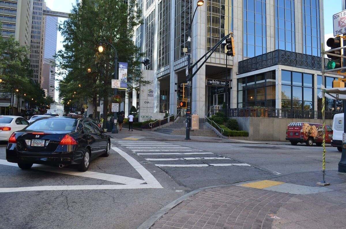 A city street with a crosswalk, traffic lights, and buildings.