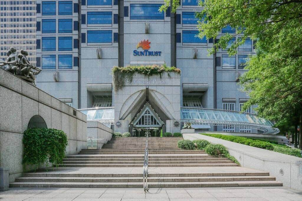 A building with a large 'SunTrust' sign, a set of stairs leading to the entrance, and a glass bridge to the right.