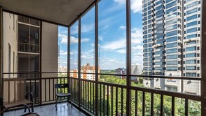 A balcony with a view of a cityscape, including high-rise buildings and greenery.