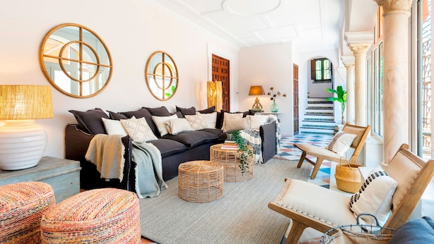 A spacious living room with a sofa set, wicker ottomans, and a coffee table. - Genteel Home San Isidoro Terrace (Seville)