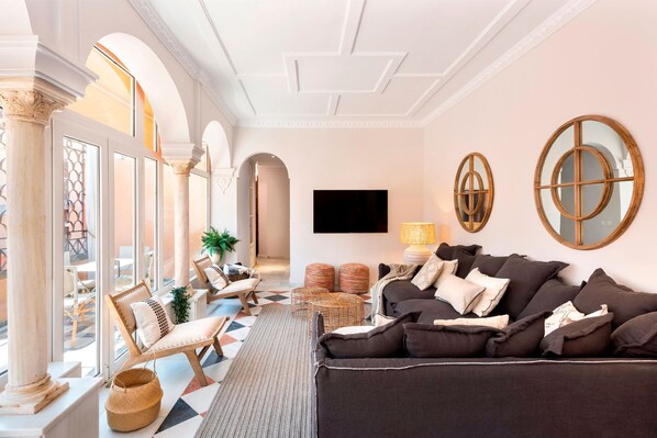 A spacious living area with a large sofa, a television, and a patterned rug. - Spectacular 3BD duplex in heart of Seville. San Isidoro Terrace (Seville)