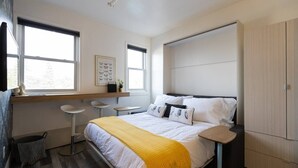 A modern bedroom with a bed, bedside tables, a desk, and a wardrobe. - Sparkling Clean, Cozy and Comfortable in Highlands (Edmonton)