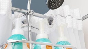 A bathroom with a shower head, a metal rack holding bottles of shampoo and conditioner, and a towel rack. - Sparkling Clean, Cozy and Comfortable in Highlands (Edmonton)
