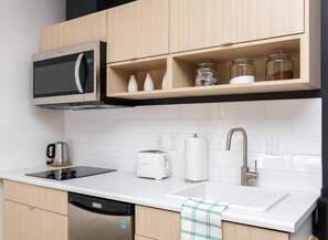 A modern kitchen with a microwave, toaster, kettle, sink, and cabinets.