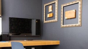 Ein modernes Zimmer mit einer dunkelgrauen Wand, einem flachbildfernseher über einem Holztisch und zwei gerahmten Bildern an der Wand.