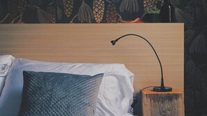 Ein ordentlich bezogenes Bett mit einem strukturierten Kissen und einem Nachttisch mit einer Lampe.