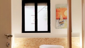 A bedroom with a wooden headboard, a bed with white bedding, a window with black frames, and a painting on the wall. - Villa (Torre Vado)