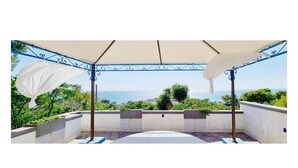 A covered outdoor patio with a view of the sea, featuring a pergola with white fabric shades and a tiled floor. - Villa (Torre Vado)